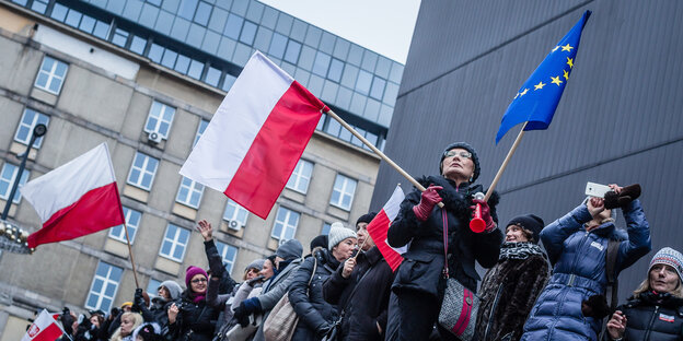 Menschen schwenken Polnische und Europäische Fahnen in Warschau