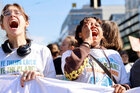 Junge Frauen rufen bei einer Demo und halten einen Banner