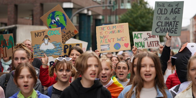 Junge Demonstranten halten Pappschilder hoch