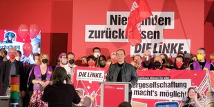 Zahlreiche Menschen stehen auf der Bühne beim Parteitag der Linken, am Redner*innenpult Lena Kreck