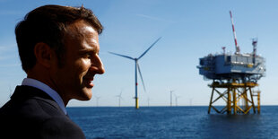 Macron im Halbprofil vor Meer und Windrädern