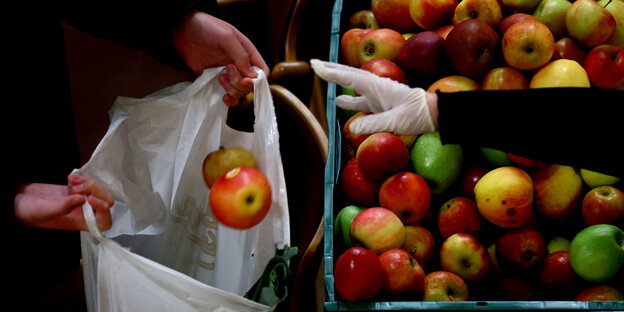 A hand throws an apple into a bag