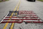 Eine gelöcherte US-Flagge liegt auf der Straße