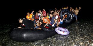 Männer in einem überfüllten Schlauchboot am Strand