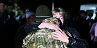 Ein Mann in Armeejacke umarmt eine Frau