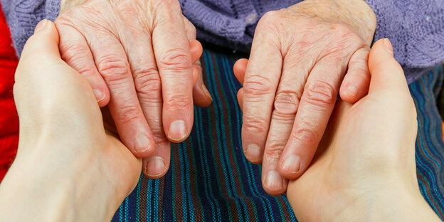The hands of an older person in the hands of a younger person