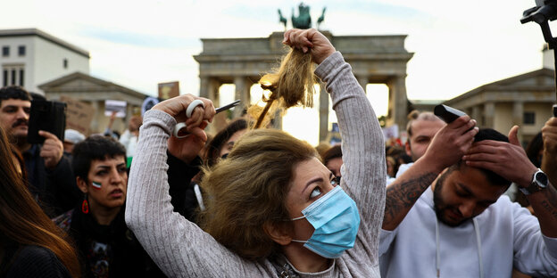 Frau schneidet sich bei einer Demonstration am Brandenburger Tor die Haare ab aus Solidarität mit den Protestierenden in Iran