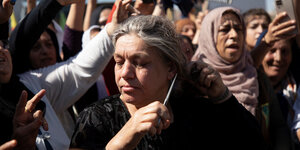 Eine Frau in einer protestierenden Menge schneidet sich Haare ab