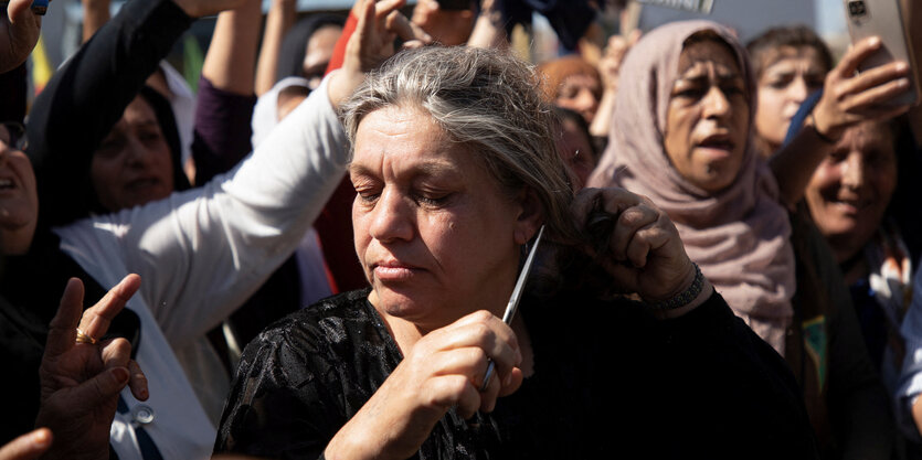 Eine Frau in einer protestierenden Menge schneidet sich Haare ab