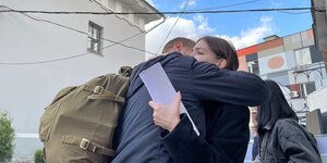 Jewgeni umarmt seine Frau zum Abschied, den Rucksack auf der Schulter