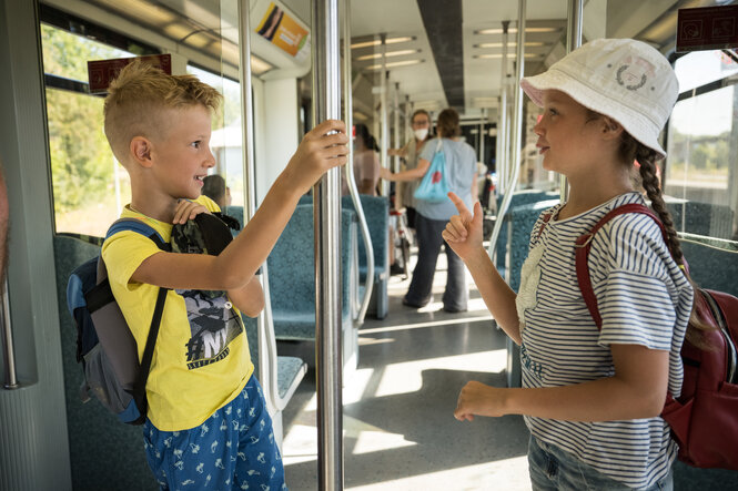 Zwei Kinder stehen sich in einer S-Bahn gegenüber