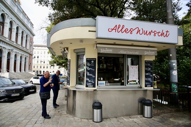 Ein Wurststand, davor ein paar Kunden, darüber der Schriftzug "Alles Wurscht"