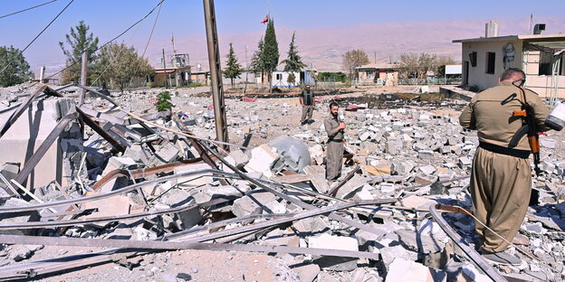 Armed people stand on a pile of rubble