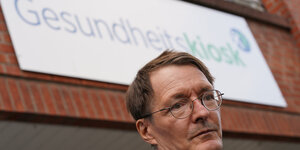 Karl Lauterbach vor einem Gebäude mit der Aufschrift "Gesundheitskiosk>"