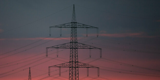 Strommasten stehen vor dem Sonnenaufgang.
