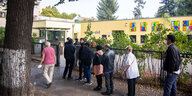 Menschen stehen vor einem Wahllokal Schlange
