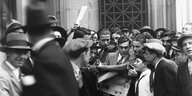 Menschenmenge liest nach dem Börsencrash 1929 aufgeregt Zeitung
