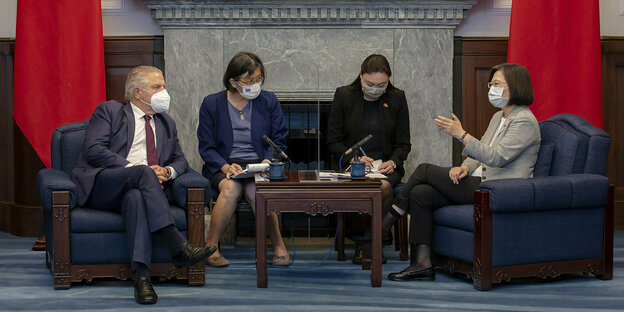 Four people with masks sit at a table