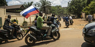 Männer in Burkina Faso auf Motorrädern, einer trägt eine russische Fahne.