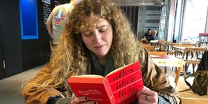 eine junge Frau liest im Café ein Buch über die Liebe