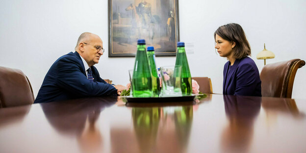 Zbigniew Rau, the Polish Foreign Minister and Annalena Baerbock are sitting at a table with drinks between them