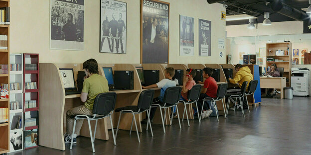 SchülerInnen sitzen in Kabinen und arbeiten am Computer