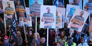 Teilnehmer einer Demonstration gegen die Energiepolitik der Bundesregierung laufen am Abend mit Schildern, auf denen Politiker in Häftlingskleidung abgebildet sind