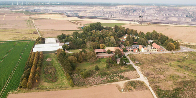 Blick auf eine Ortschaft, dahinter die Landschaft eines Tagebaus