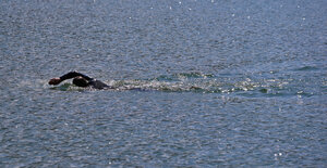 Das Foto zeigt einen Schwimmer im Neoprenanzug in einem See.