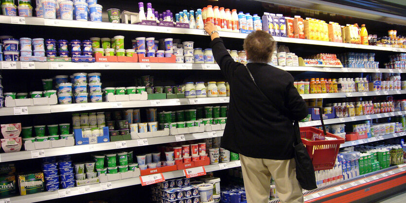 Mann reicht ins obere Fach des regals im Supermarkt