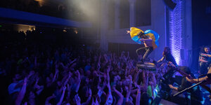 Eugene Hüt, verhüllt mit ukrainischer Flagge bei einem Konzert, er wird von den Zuschauern auf einer Trommel stehend getragen