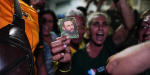 Ein junger Mann schreibt und hält ein kleines Foto von Fidel Castro in die Kamera