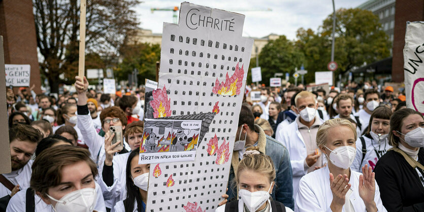 Demonstrant*innen mit dem Schild einer brennenden Charité.