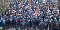 Polizisten halten eine Menschenmenge auf