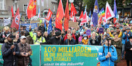 Teilnehmer einer Friedens-Demonstration stehen zu Beginn der Demonstration in Hamburg mit Fahnen und Transparenten zusammen.