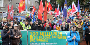 Teilnehmer einer Friedens-Demonstration stehen zu Beginn der Demonstration in Hamburg mit Fahnen und Transparenten zusammen.