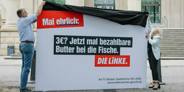 Lars Leopold und Jessica Kaußen enthüllen ein Wahlplakat mit der Schrift: Mal ehrlich: 3E? Jetzt mal bezahlbare Butter bei die Fische.