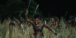 Eine schwarze Kriegerin in Amazonenrüstung, von unten fotografiert