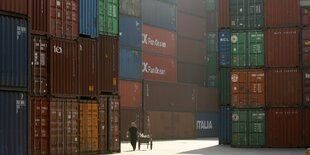 Eine Frau läuft am Hafen in Schanghai an Containern vorbei.