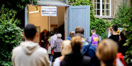 Das Foto zeigt eine Schlange wartender Wahlwilliger vor einem Wahllokal.