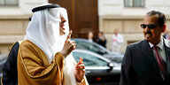 Der saudische Energieminister steht mit erhobenenem Zeigefinger auf der Straße und spricht mit einem Mann, der eine Sonnenbrille trägt
