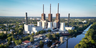 Ein Heizkraftwerk an einem Fluss aus der Vogelperspektive mit drei Schornsteinen an einem sonnigen tag