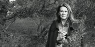 Annie Ernaux steht im Jahr 2002 zwischen Nadelbäumen - schwarz-weiss Aufnahme