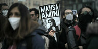 Protest in Berlin mit einem Plakat das Mahsa Amini zeigt