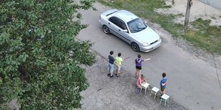 Luftaufnahme von Kindern, die am Straßenrand ein Auto anhalten