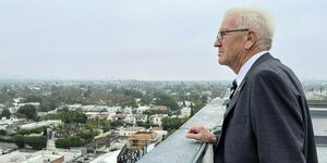 Ministerpräsident Winfried Kretschmann steht auf dem Dach eines Hotels und blickt in die Ferne.