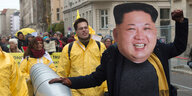 Demo mit Menschen in gelben Anzügen, einer Raketenattrappe und einer Person mit dem Konterfei von Kim Jong Un