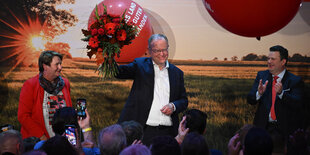 Stephan Weil mit Blumen auf einer Bühne, daneben Arbeitsminister Hubertus Heil