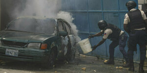 Polizisten mit schusssicheren Westen und Helmen löschen ein Auto in Port-au-Prince, Haiti