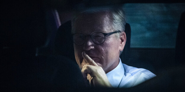 Bernd Althusmann sitzt im Auto, einen Finger versonnen an den Mund gelegt. Er wirkt nachdenklich